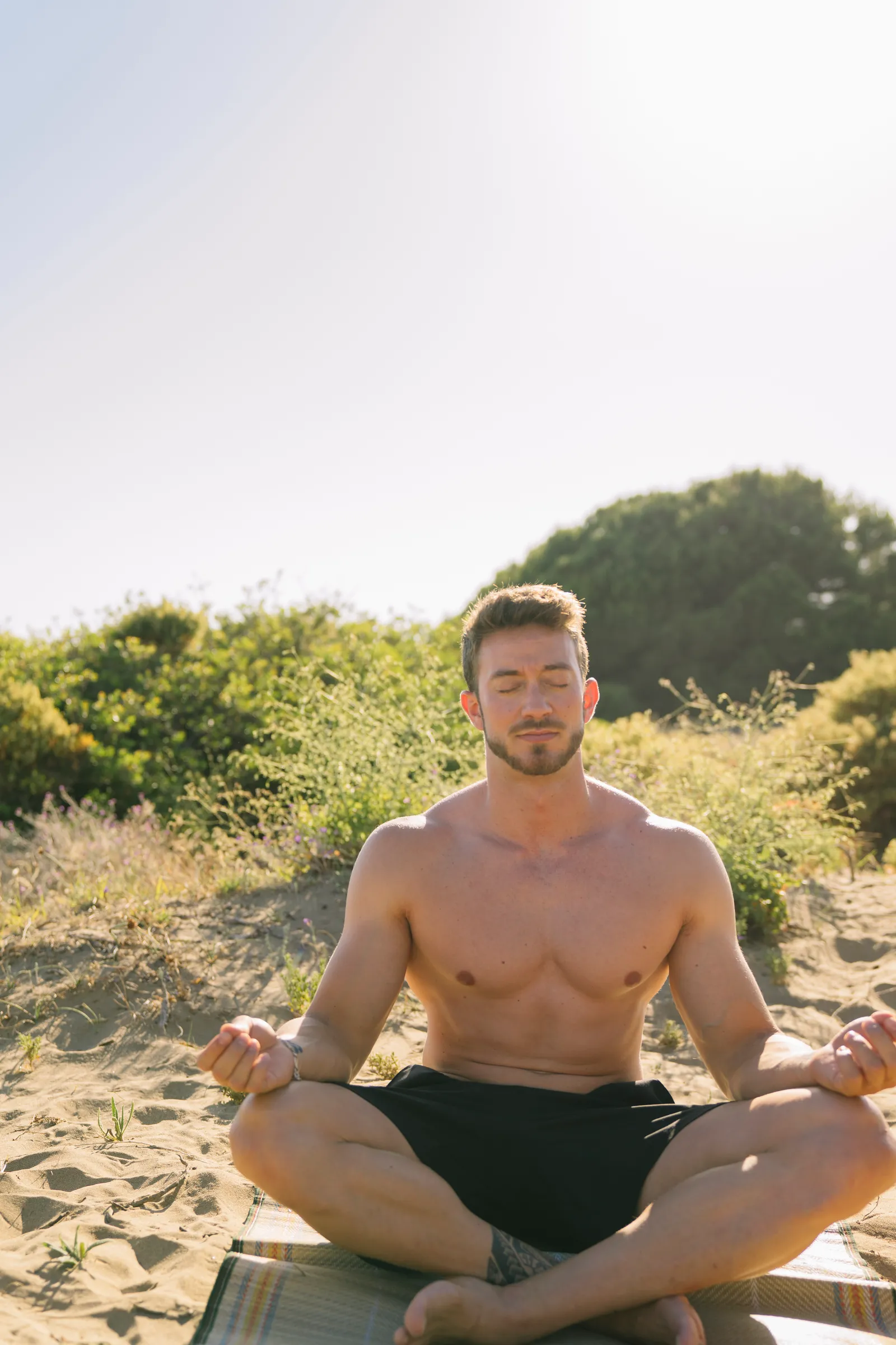 Hombre meditando en la playa al amanecer
